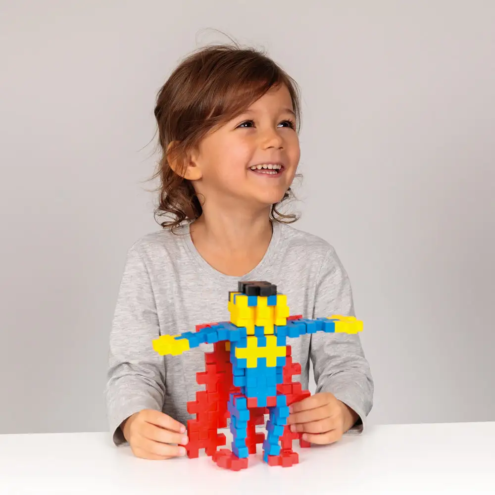 Fillette jouant avec un super héros fabriqué avec le jeu de construction Plus-Plus BIG